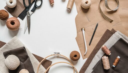 Flat lay of craft materials and recycled paper, with scissors, thread and a tape measure.
