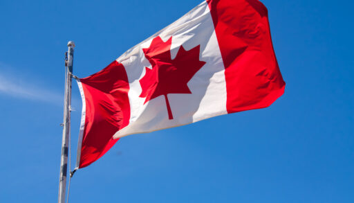 Canadian flag against a blue sky waving in the wind.