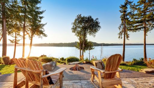 back-yard-of-waterfront-house-with-adirondack-chairs-and-fire-pit