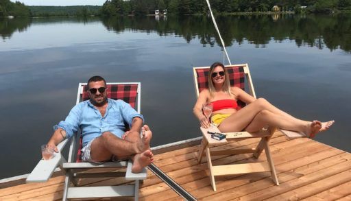 a man and a woman sitting in halihammock chairs on a dock overlooking a like