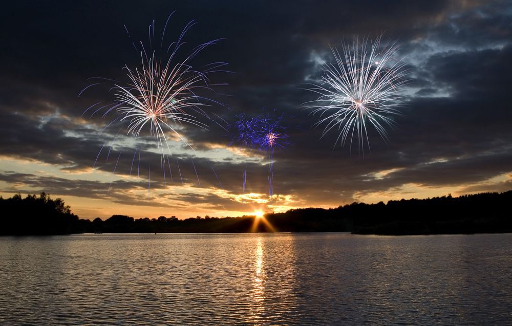 Fireworks over a lake at sunset