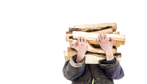 A man carrying a stack of wood, obscuring his face