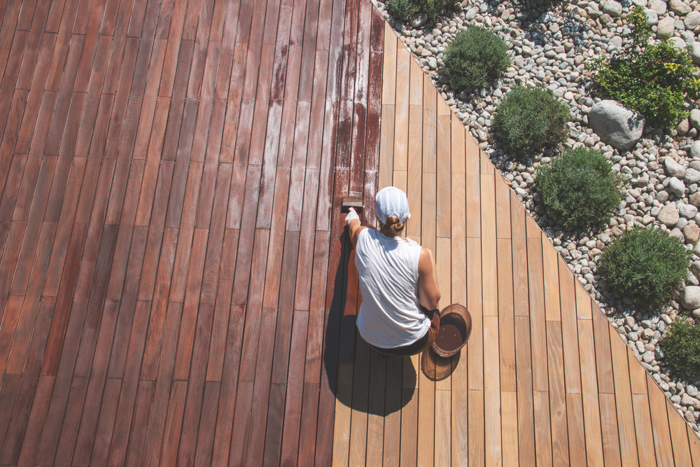 An overheard shot of someone staining a deck