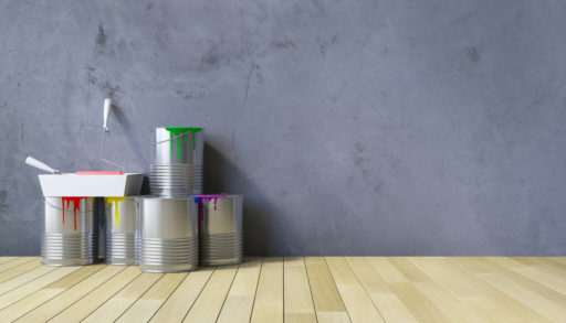 Paint cans sitting on a wood floor against a grey wall