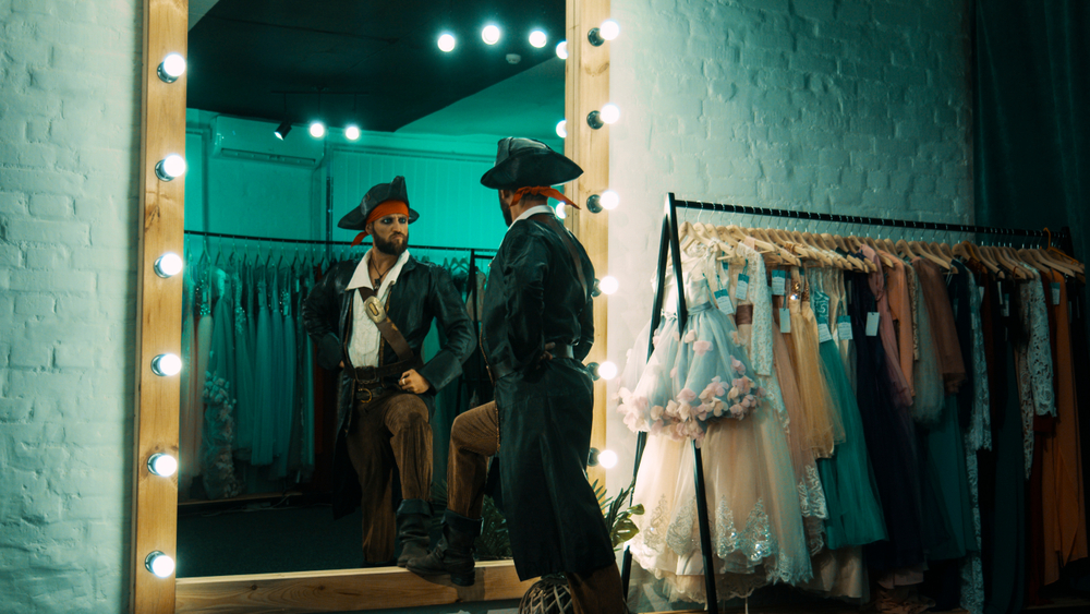 A man dressed as a pirate, standing in front of a mirror