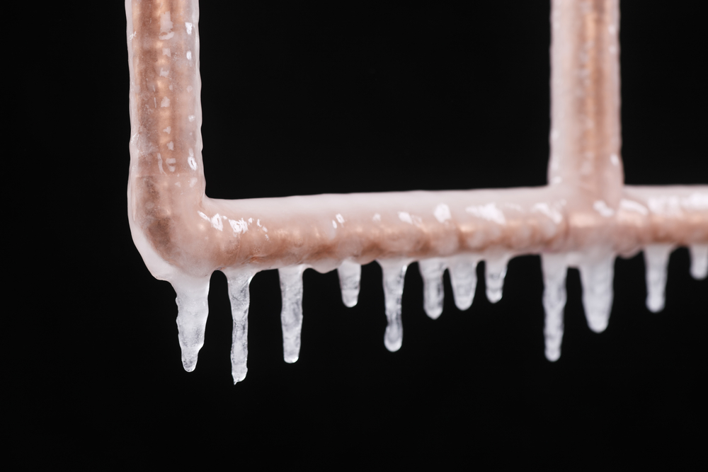 A frozen copper pipe against a black background