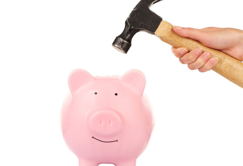 Female hand holding hammer above pink piggy bank isolated on white, closing costs