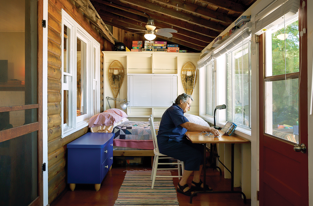 Eileen Baldwin relaxes in her nearly century-old log cabin, working at a desk