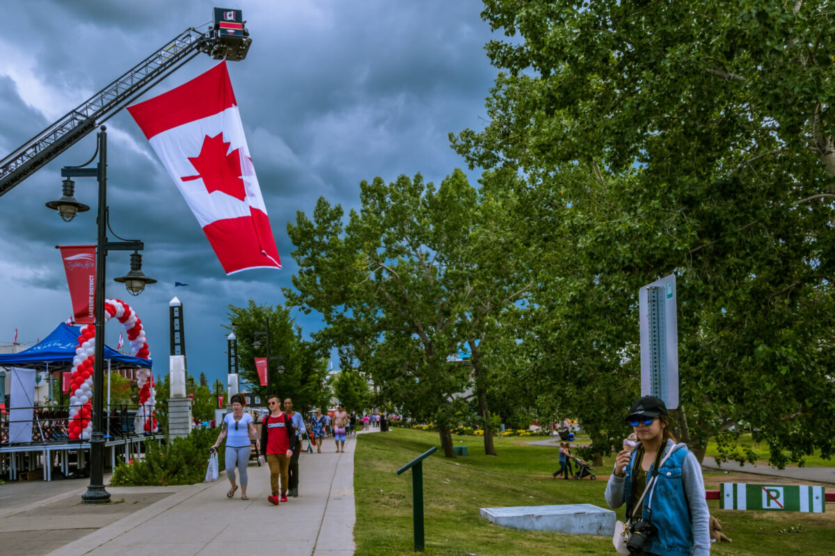 People walking along stone path under Canadian flags celebrating Canada Day