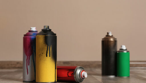 Cans of spray paint against a beige background