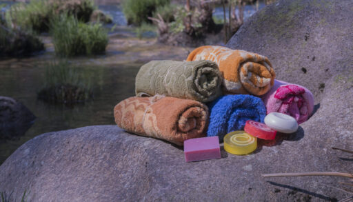 shower towels and soap on a rock by water