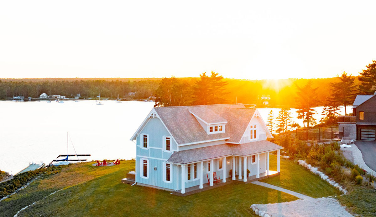 baby blue cottage exterior at sunset with water in the background