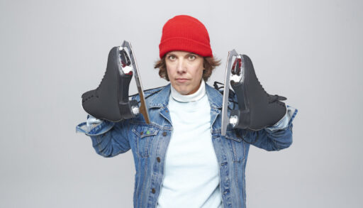 Carolyn Taylor holding up skates and wearing a red hat