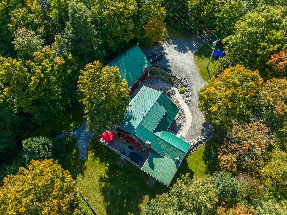 Overhead view of a big cottage with a green roof and a large driveway.