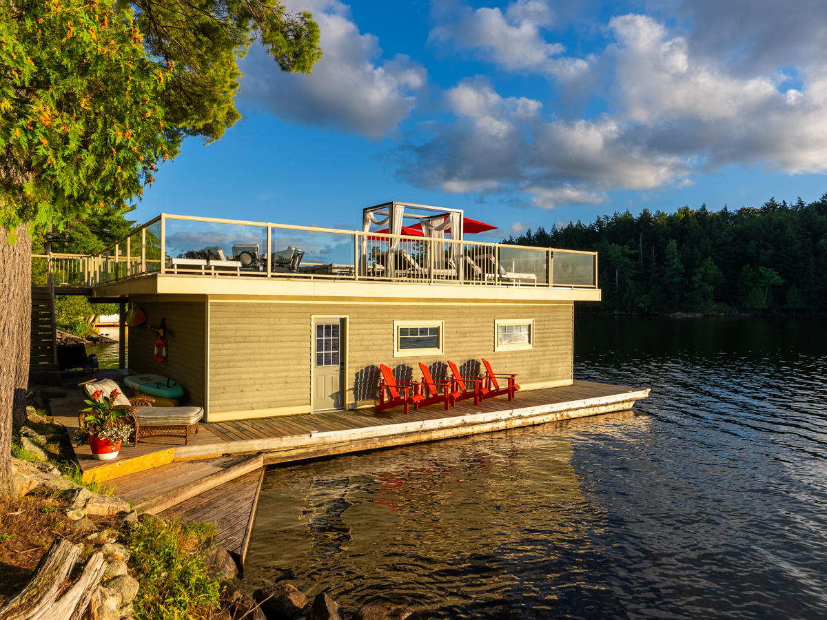 A big boathouse with Muskoka chairs along the outside and a rooftop deck.