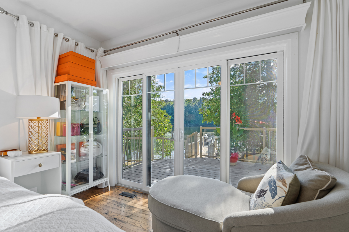 Double glass doors walkout from a bright bedroom to a deck.