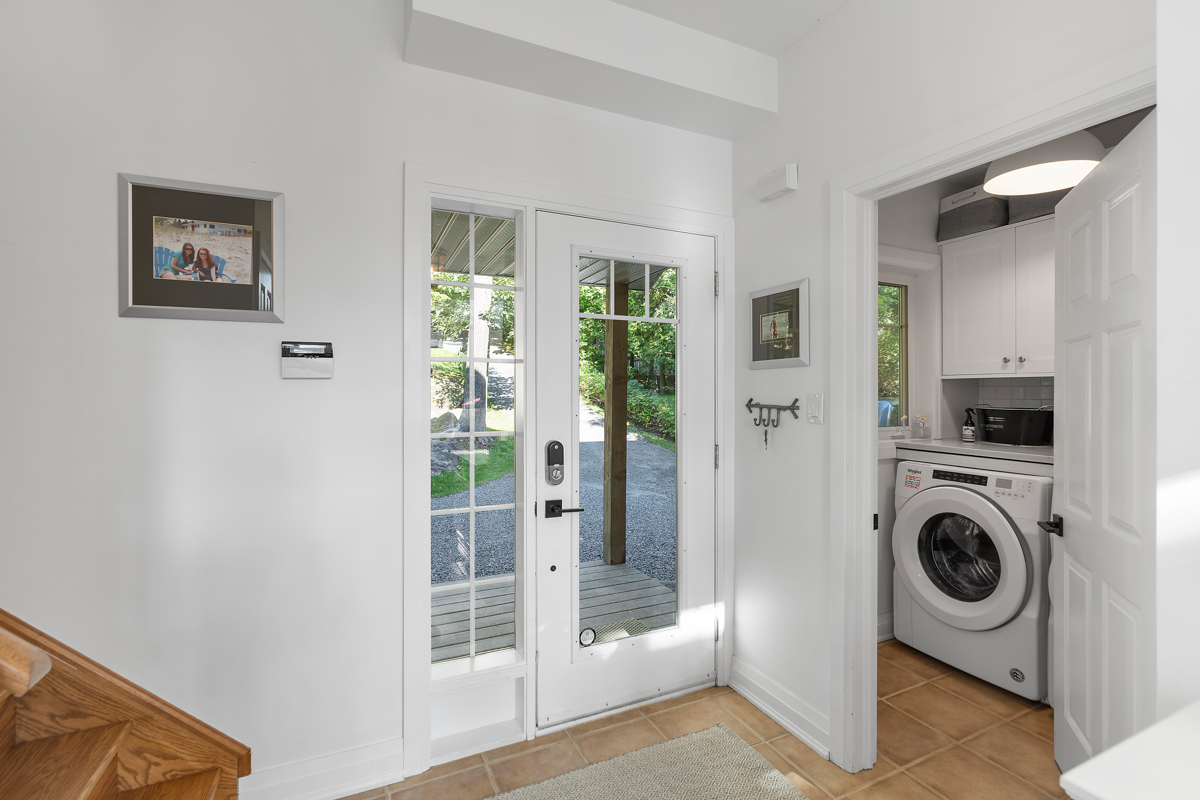 A washing machine and dryer sit in a small room beside a front door.