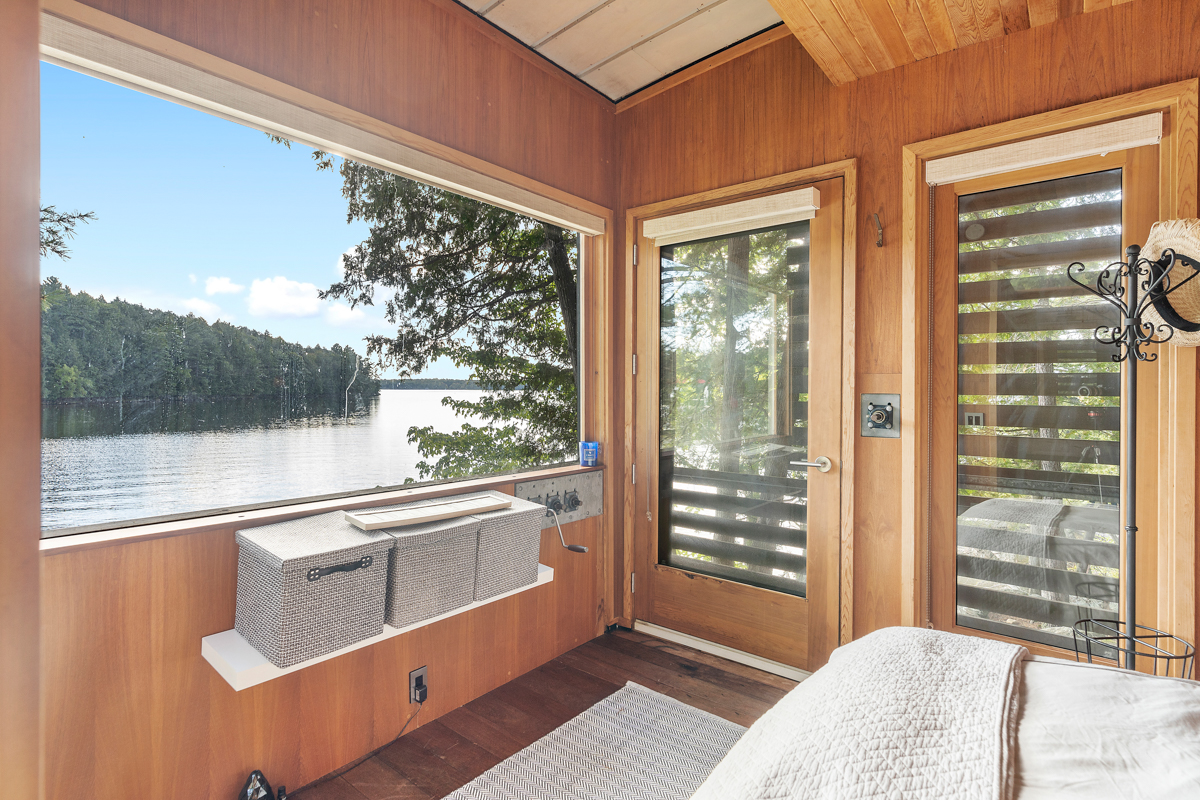 Inside a small bunkie with a large window and a view of the lake.