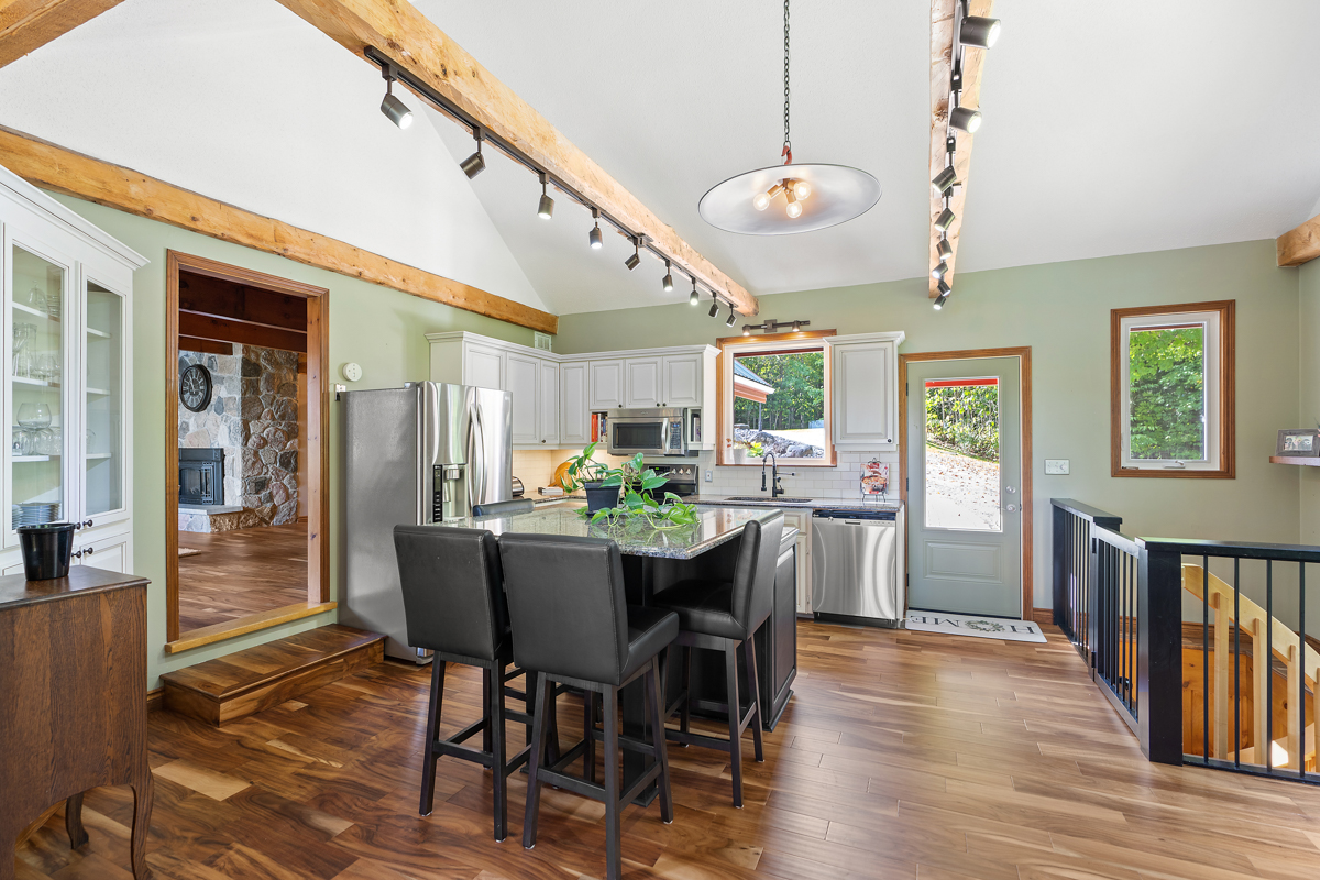 A big, updated kitchen with hardwood floors and light green walls.