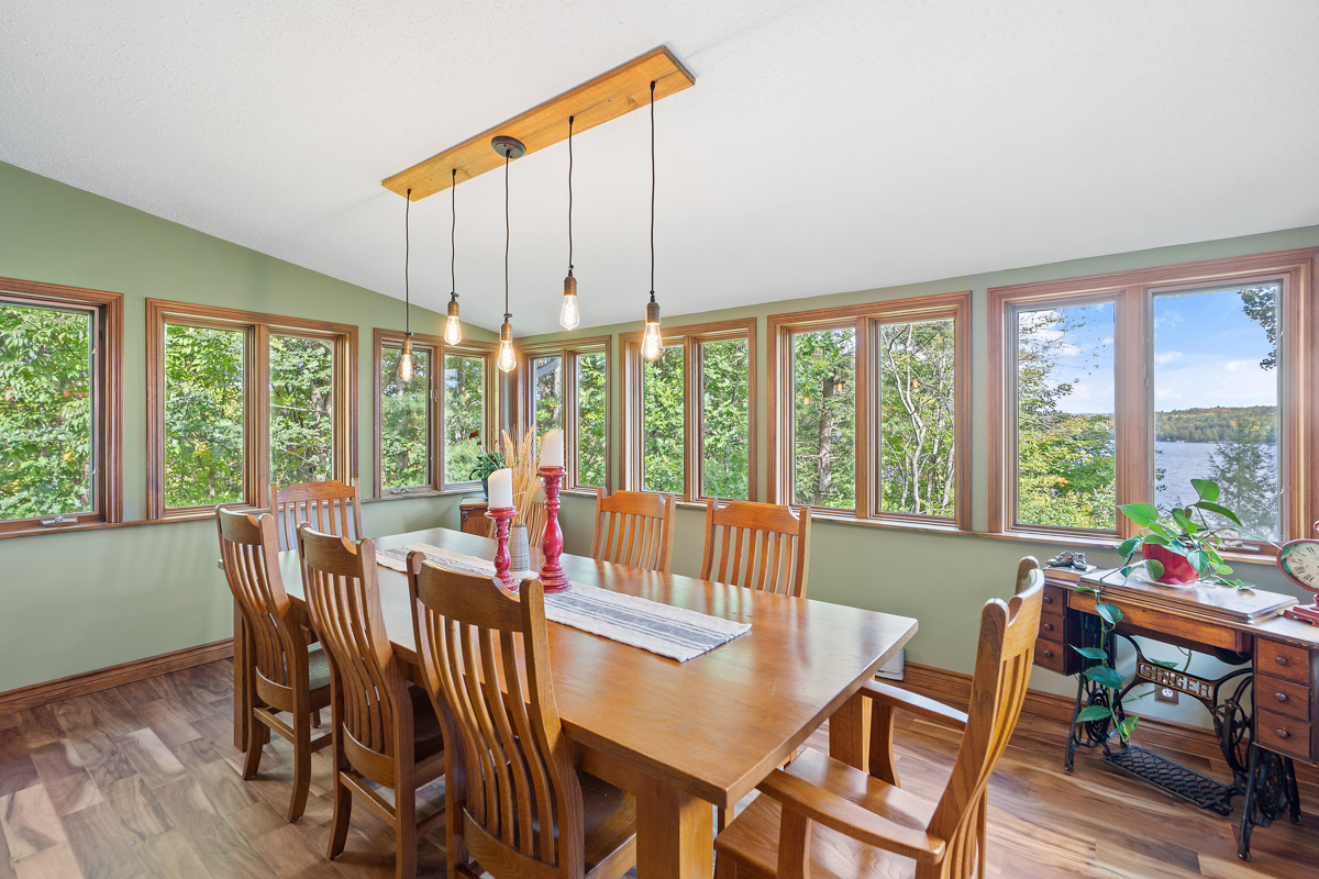 A bright dining area with a table and chairs and lots of windows on all sides.