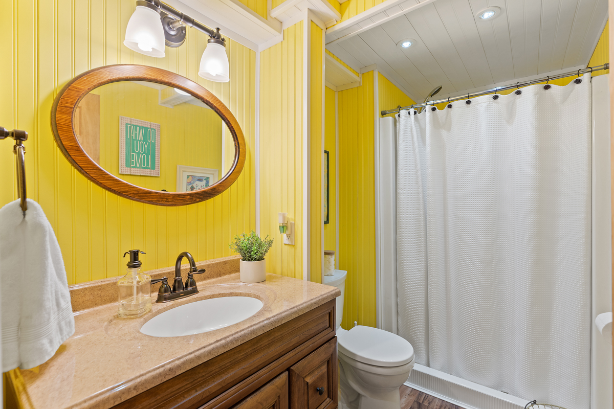 A three-piece bathroom with yellow walls, a shower-bathtub combo, a toilet, and a sink.