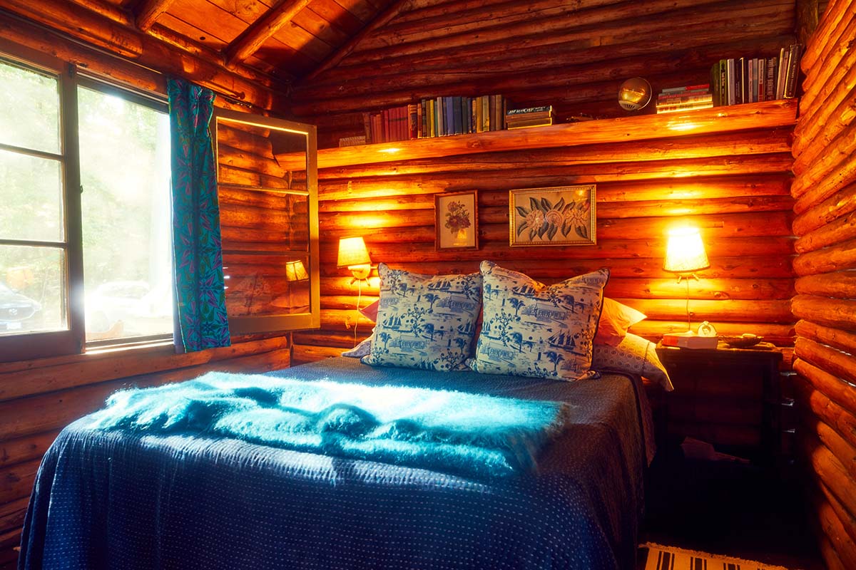 A photo of a cottage bedroom with a blue bedspread and