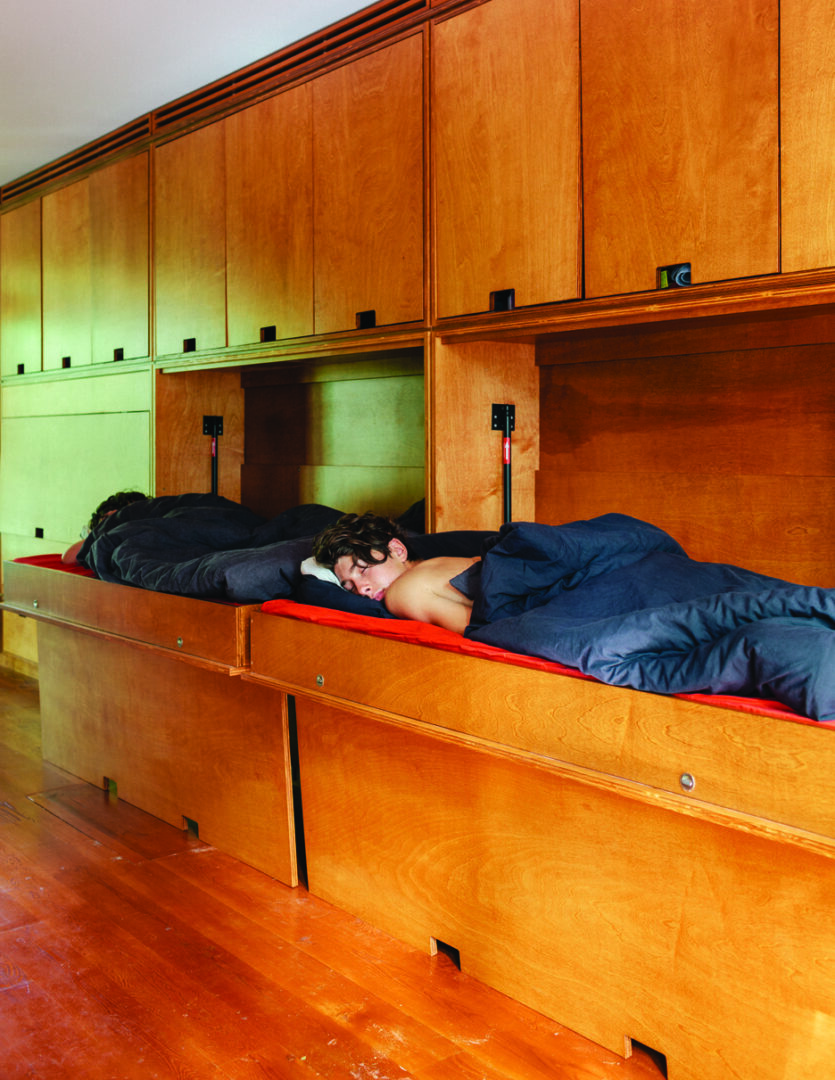 A photo of two young kids sleeping in fold-down murphy beds