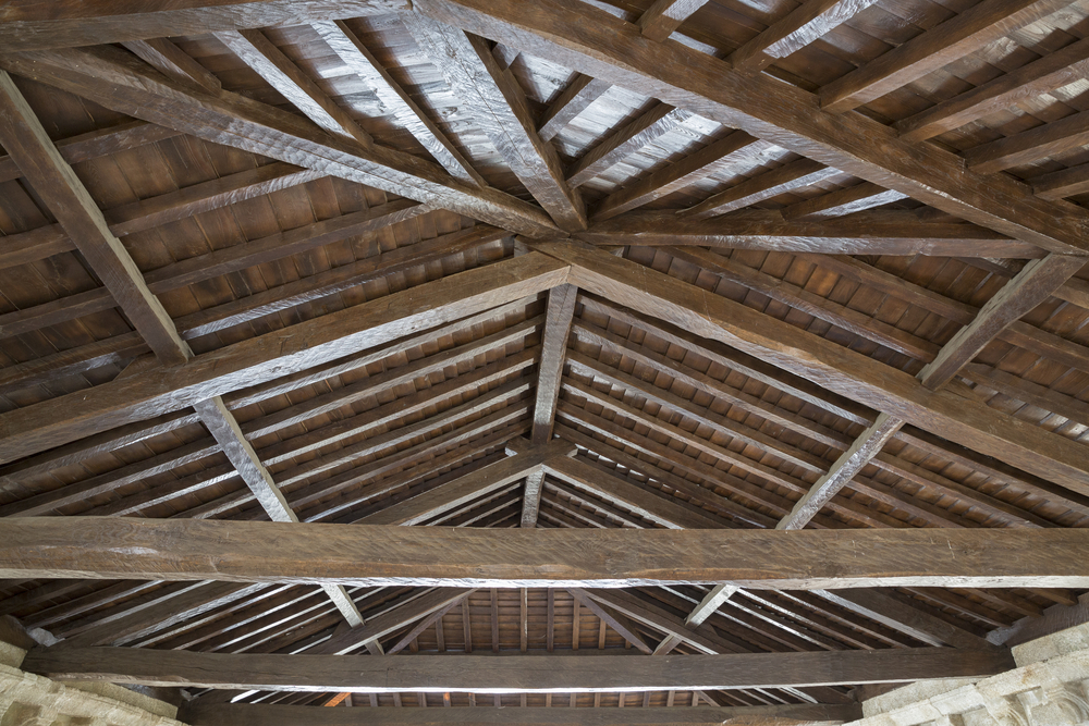 A wood ceiling with exposed rafters and joists