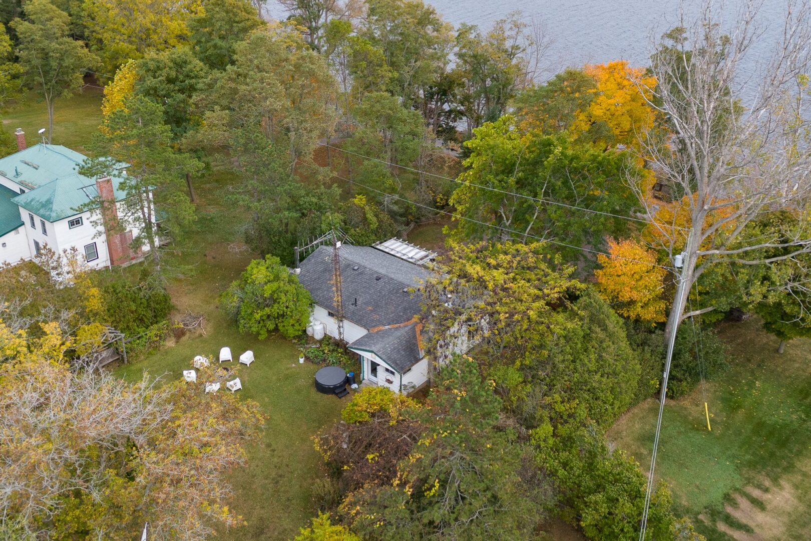 Overhead view of a lakefront bungalow surrounded by trees.