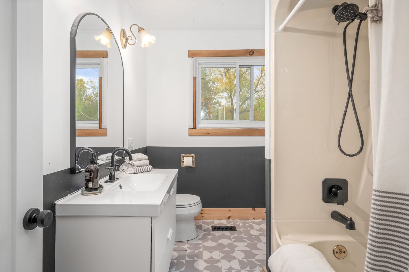A big bathroom with patterned tiled floors, a toilet, a sink, and a shower-tub combo.