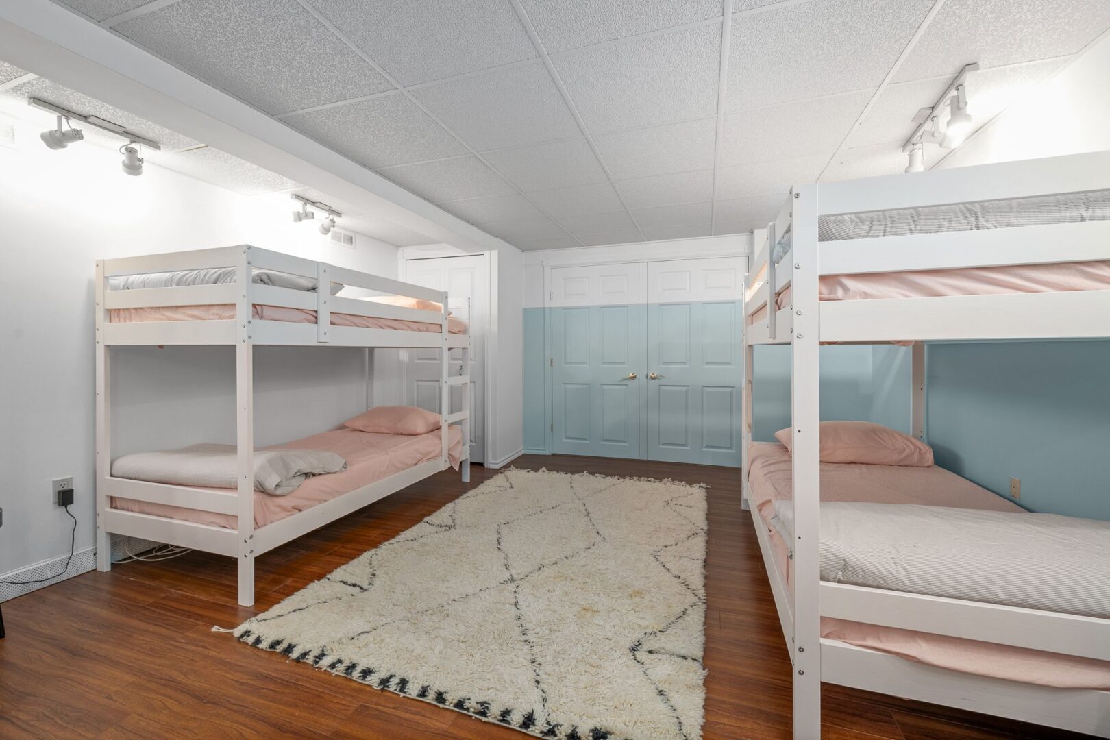 Two bunk beds in a finished basement area with light blue walls.