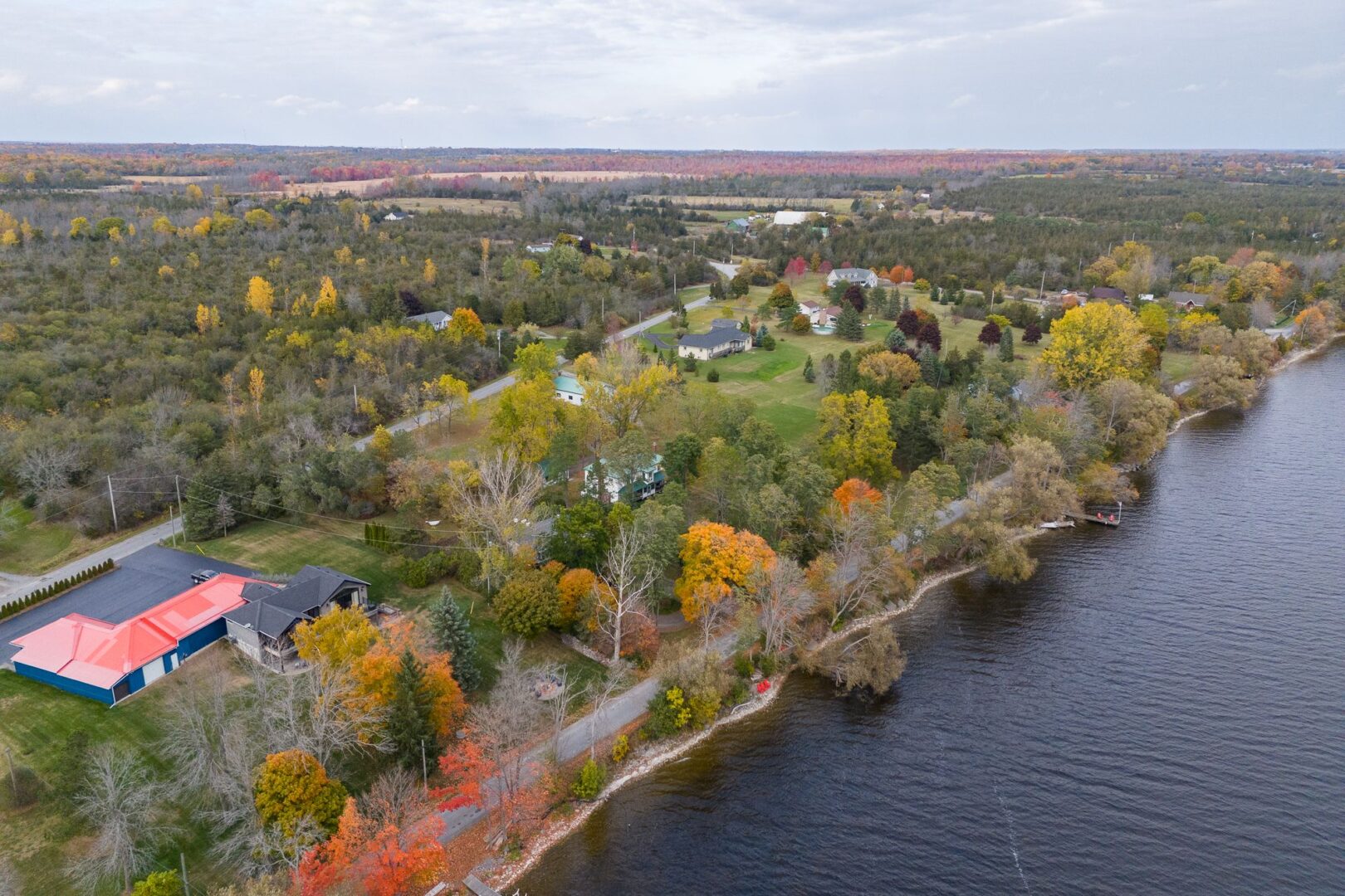 Overhead view of a green stretch of land along a lake, with a few houses lining the waterfront.