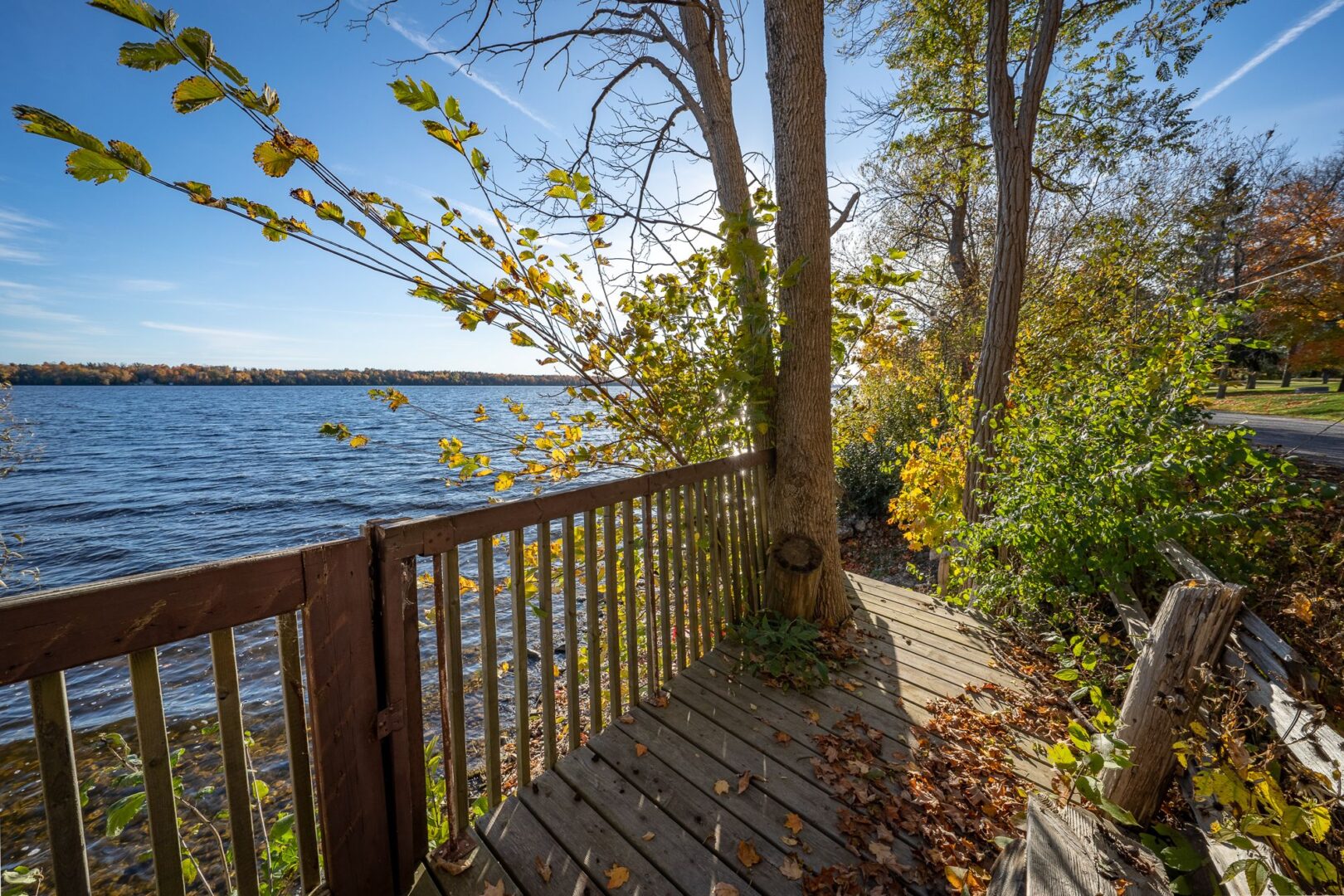 A wooden deck with a railing looks out over a stretch of lake.