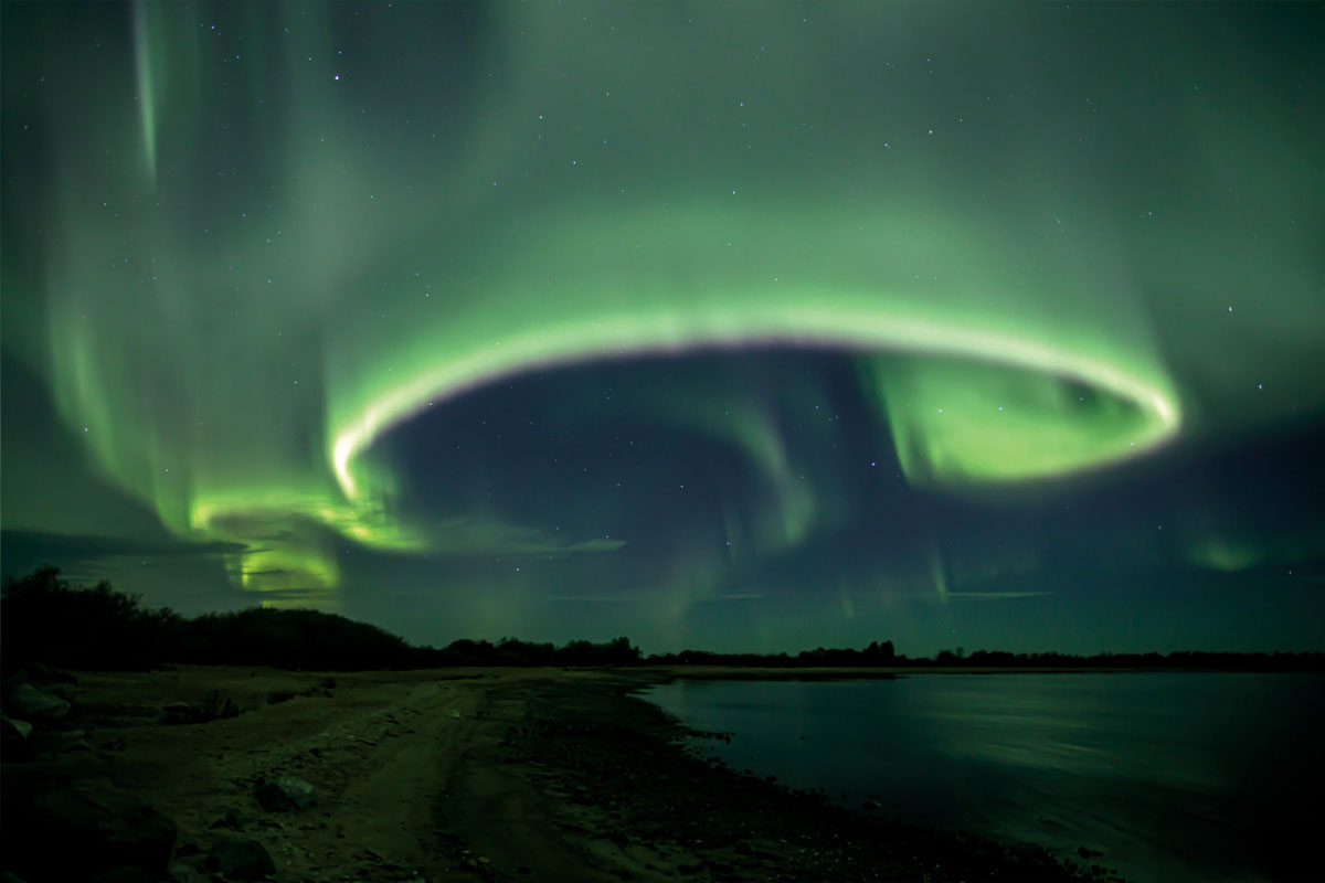 Green and blue Northern Lights at night over the shores of Lake Winnipeg