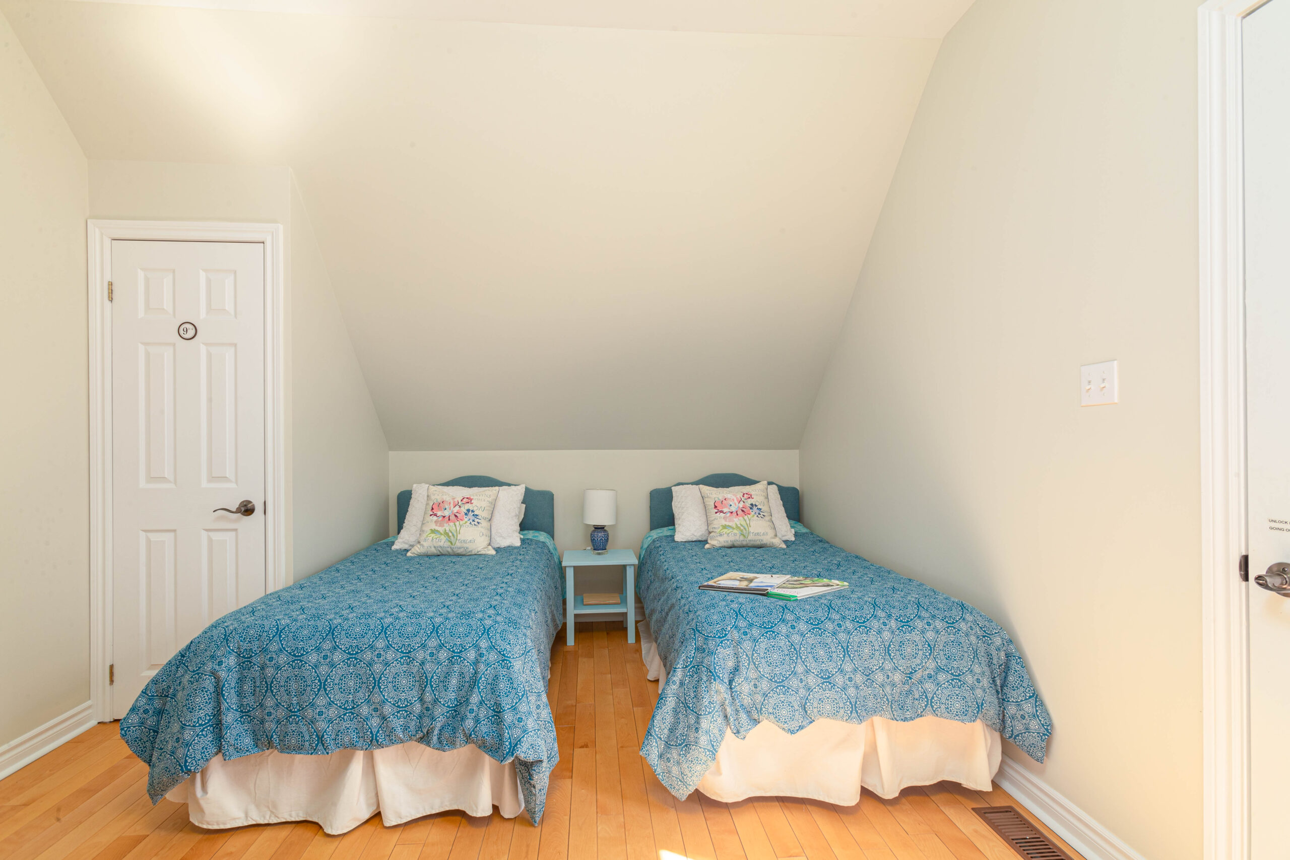 A narrow bedroom with two single beds and a sloping ceiling.