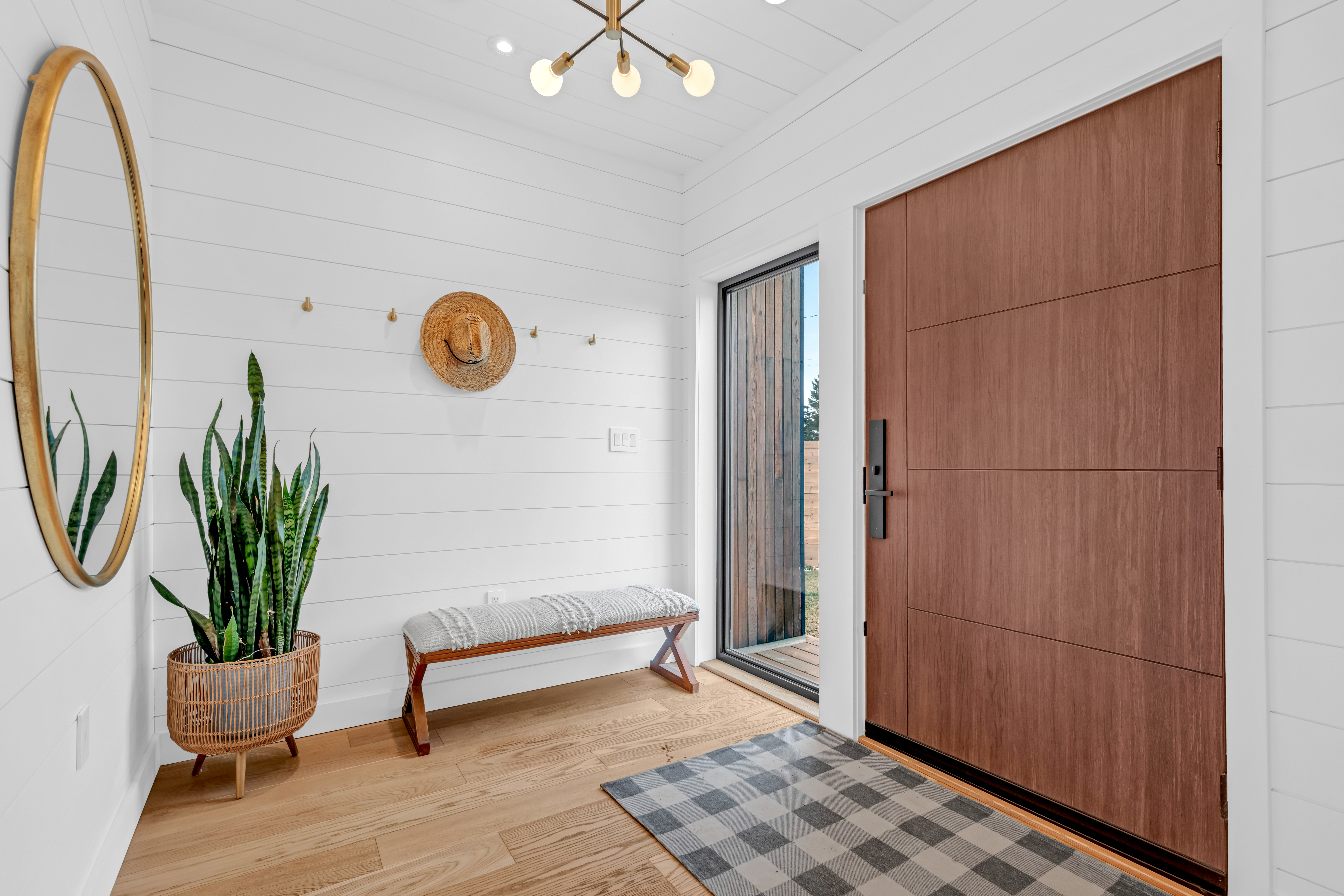 A modern front entryway with a big front door, a big window, and white-painted shiplap walls and ceiling.