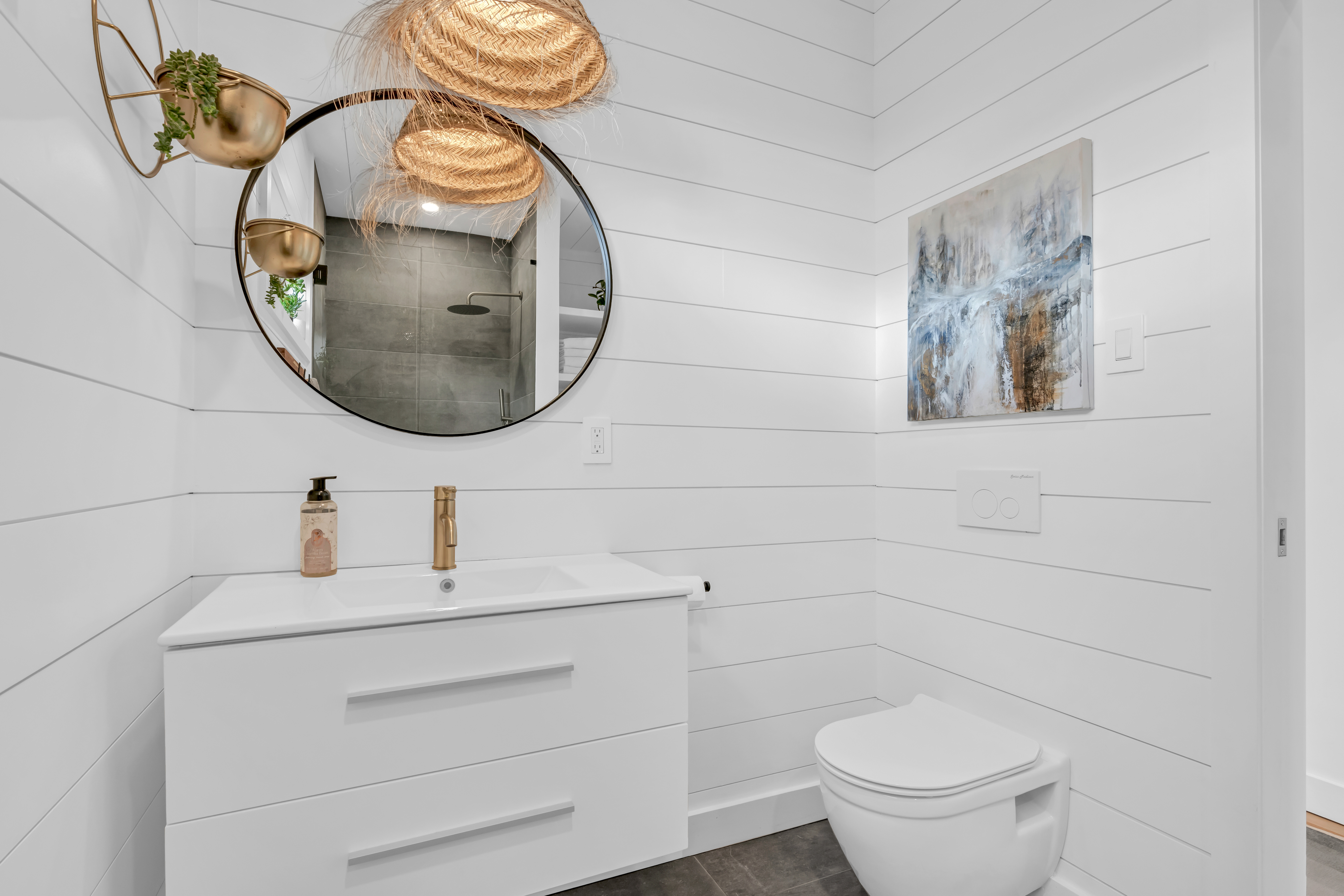 A bathroom with a toilet, a sink, a shower, and white-painted shiplap walls and ceiling.