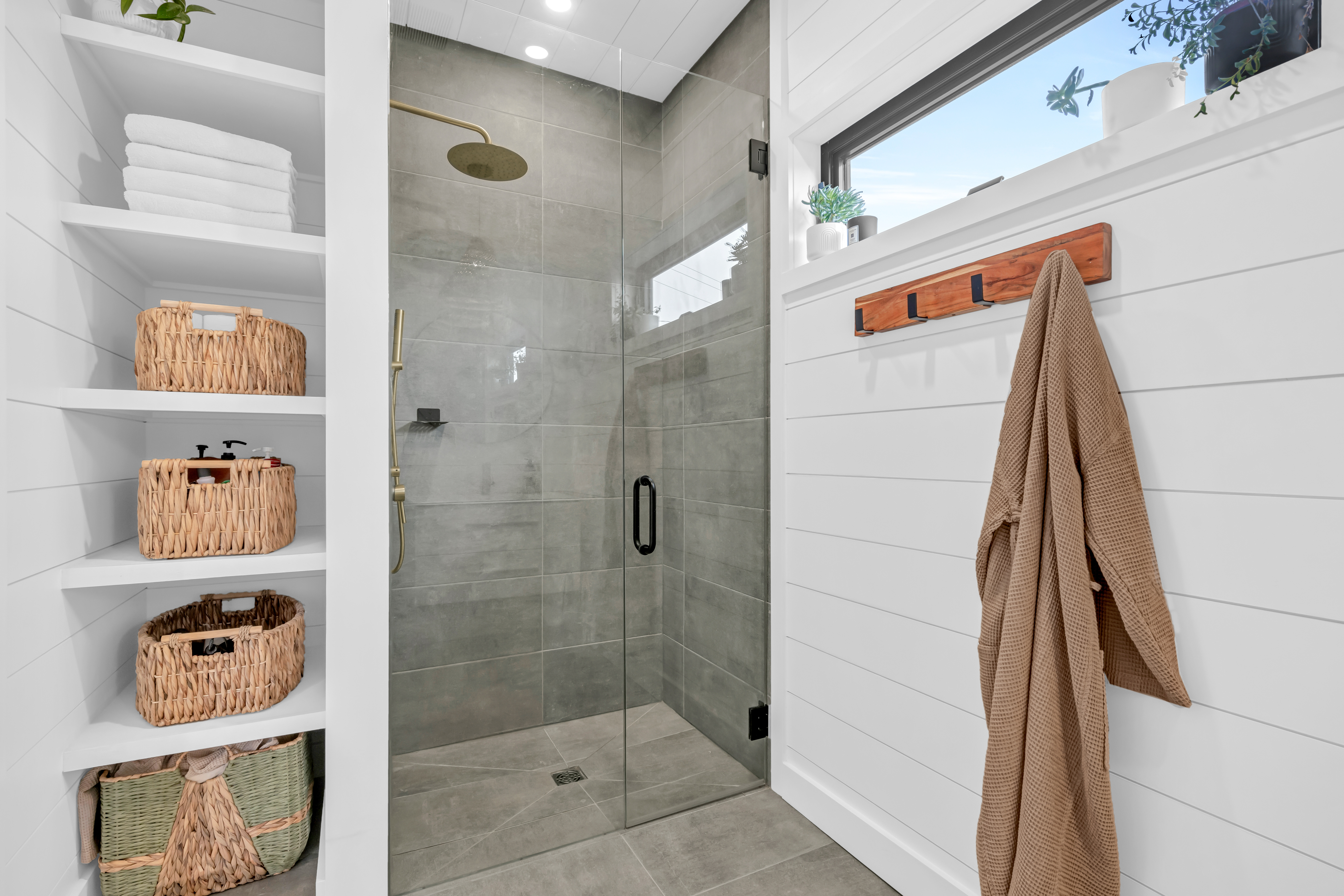 A bathroom with a spacious walk-in shower and a long window.