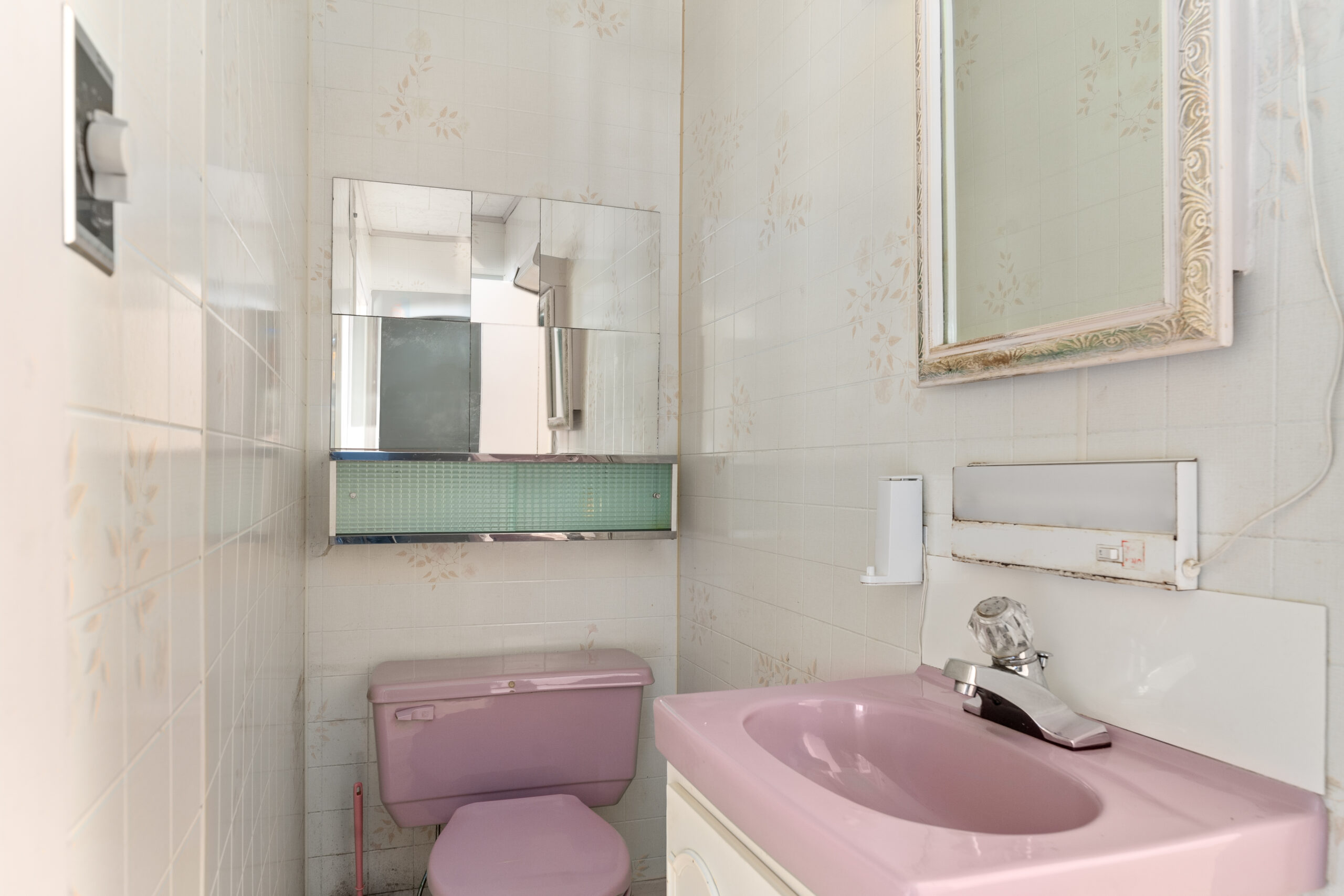 A small bathroom with a pink toilet and sink.