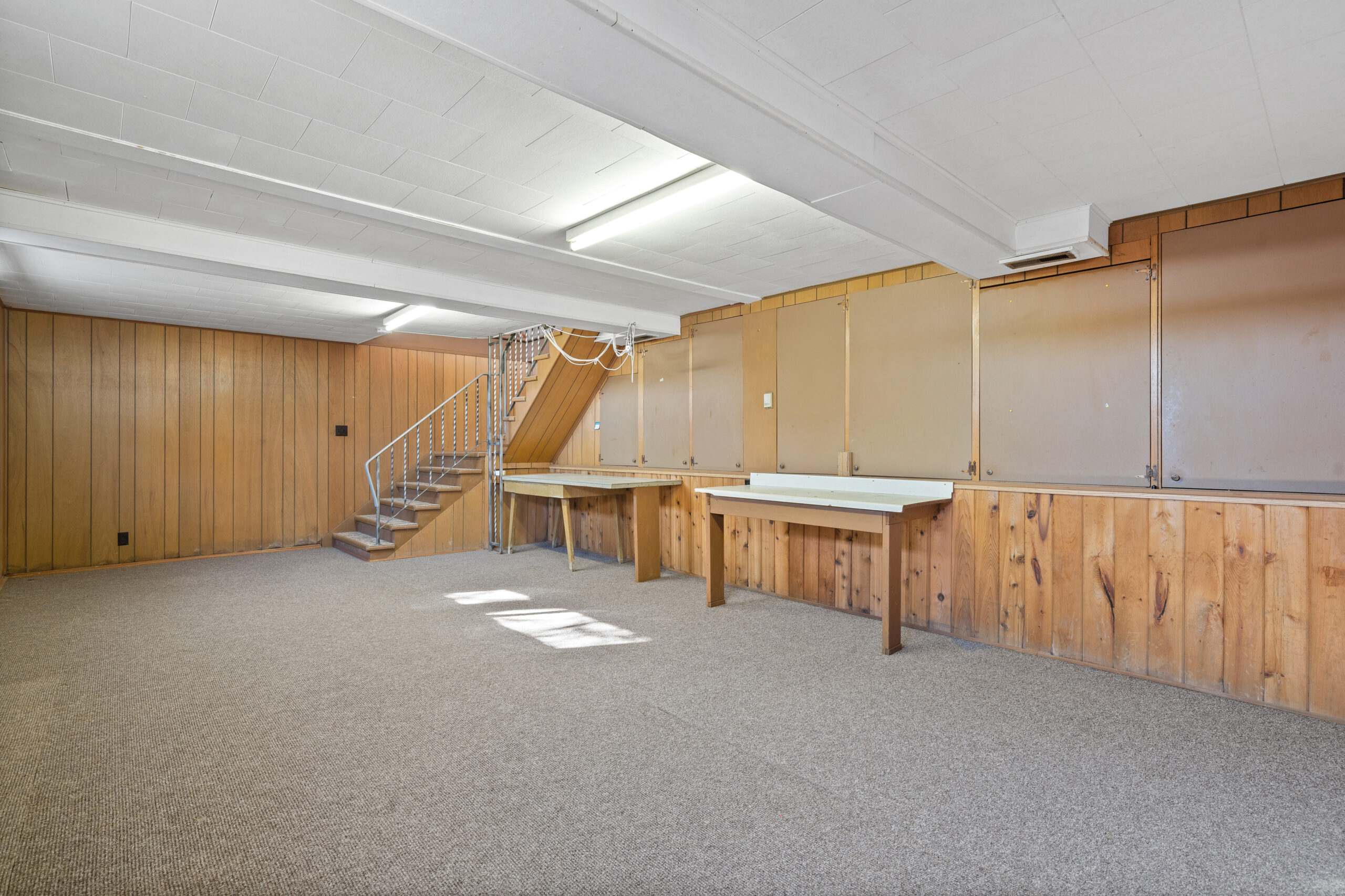 An empty lower-level rec room space with wood-panelled walls.