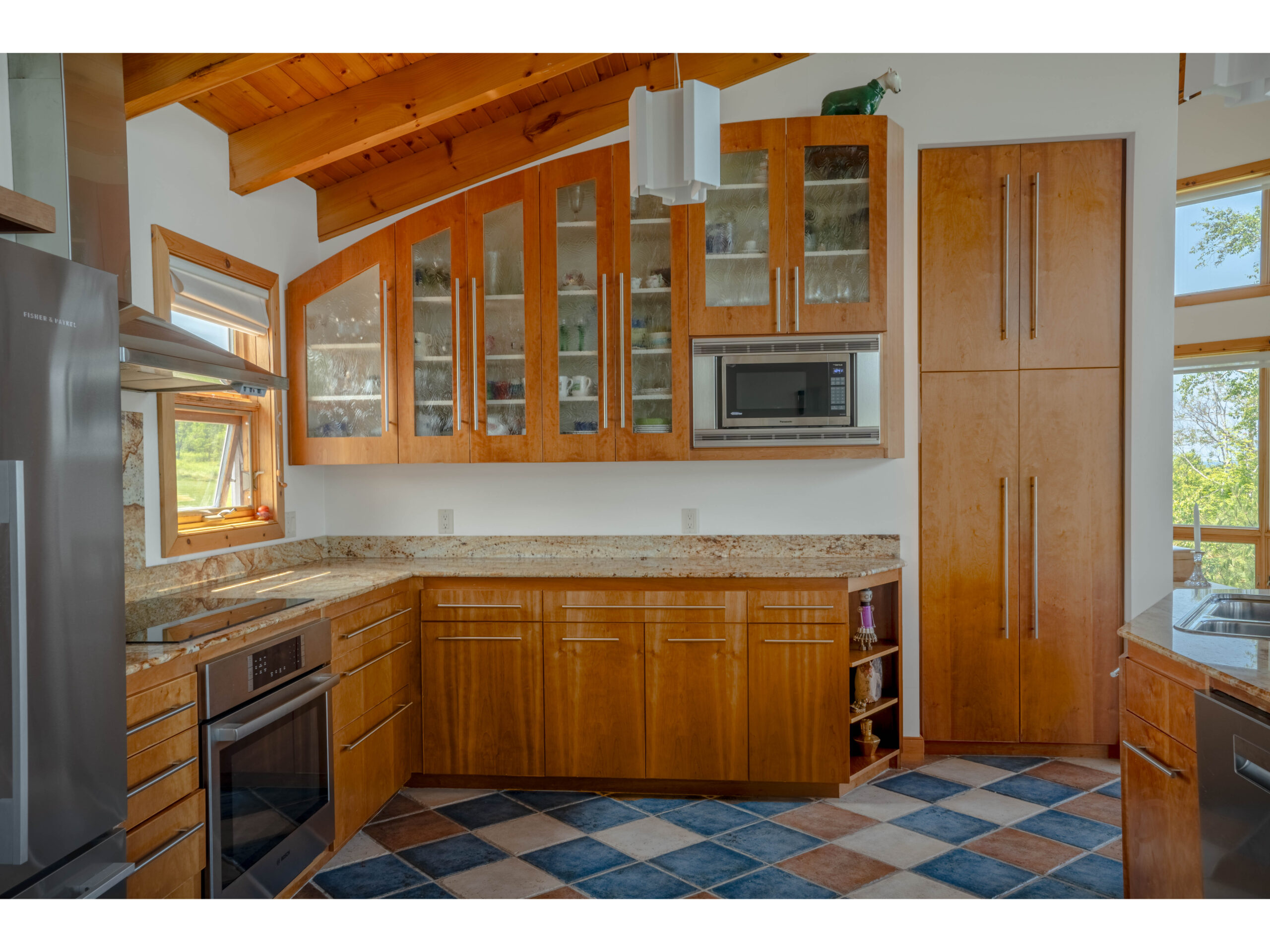A big kitchen with a colourful tiled floor, stainless steel appliances and granite countertops.