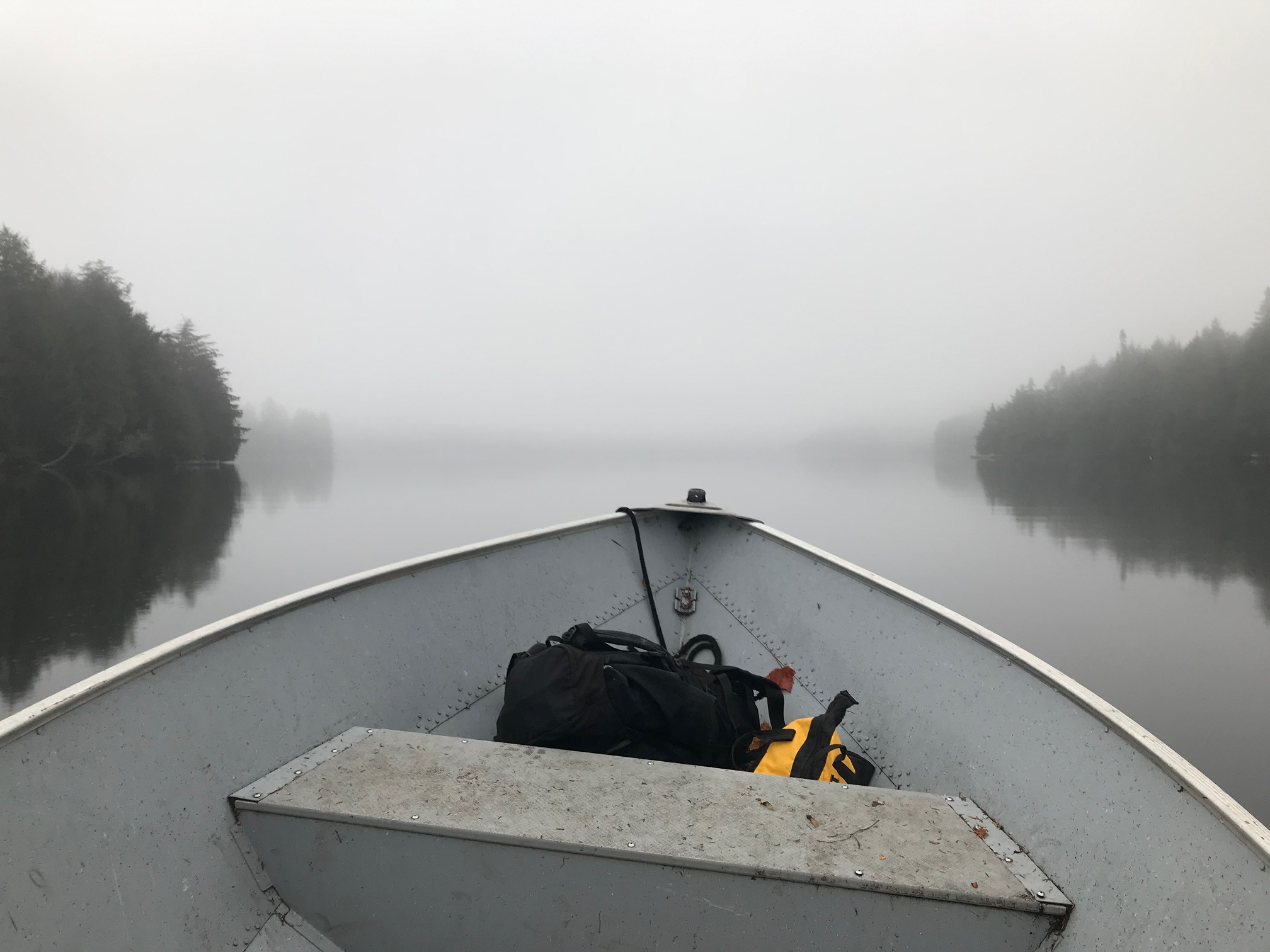 View of a still lake on a foggy day, from inside a small boat.