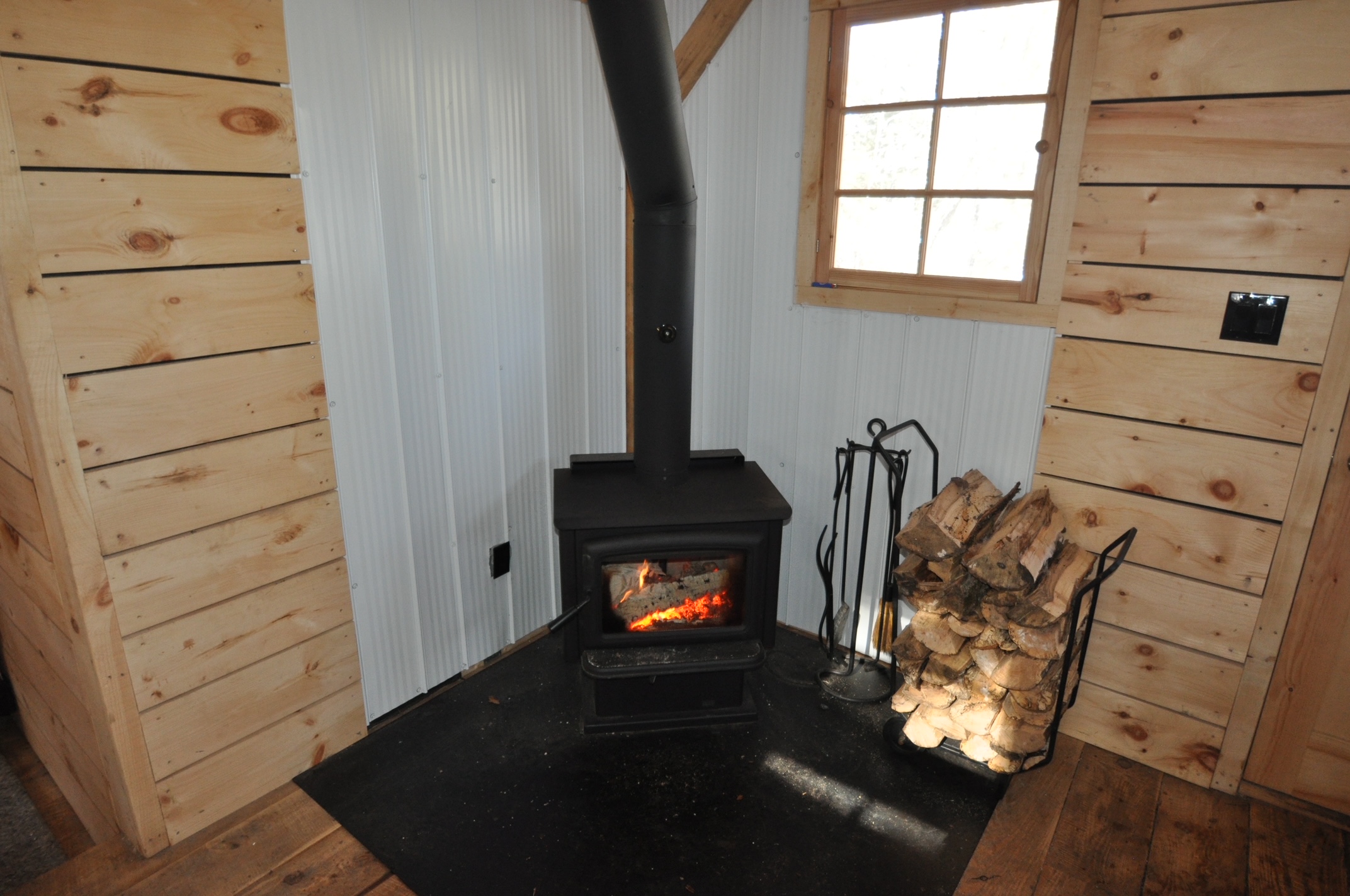 A wood stove in the corner of a cabin living area.