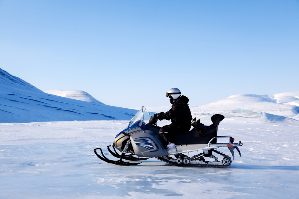 A snowmobile and rider travelling across a frozen lake